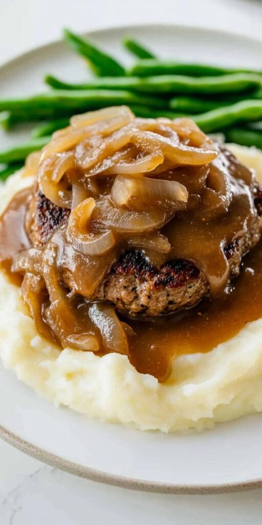 hamburger steak in rich onion gravy, served over creamy mashed potatoes with a side of fresh green beans